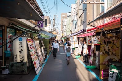 Eine Straße in Tokio, die links und rechts von kleinen Essensständen gesäumt ist.