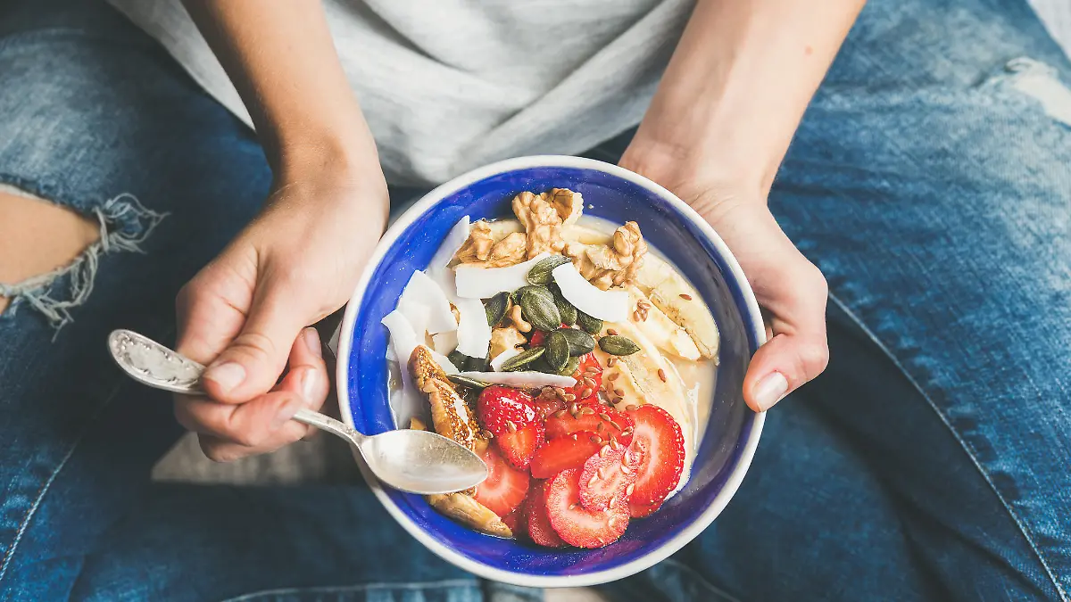Gesunde Frühstücksbowl mit Joghurt, Granola, Samen, frischen und getrockneten Früchten und Honig