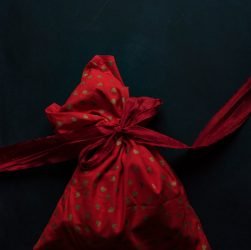 red and gold polka-dot drawstring pack on black surface