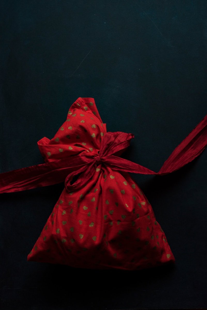 Die perfekte Spardose als Geschenk zur Geburt: Eine zeitlose Tradition mit Mehrwert red and gold polka-dot drawstring pack on black surface